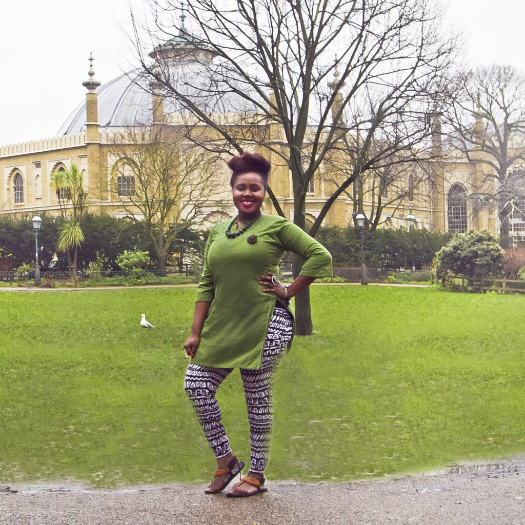 A woman stands in the Pavilion Gardens in Brighton wearing a long green tunic top over black and white print leggings