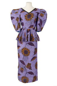 purple blouse featuring a sunflower and butterfly print, with large padded shoulders and peplum waist, worn on mannequin with matching skirt.
