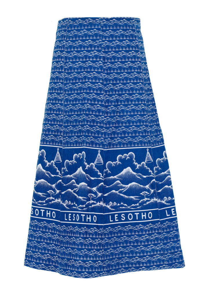 A woman's A line skirt made of blue shweshwe fabric, featuring the word 'Lesotho'