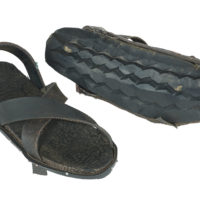 Two black rubber sandals, one turned to show that the sole is made from a car tyre