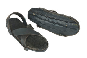 Two black rubber sandals, one turned to show that the sole is made from a car tyre