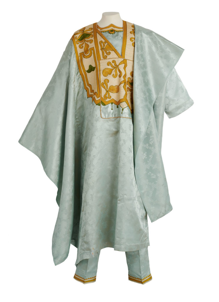 a mannequin wearing a long pale blue satin robe and matching trousers. The robe has islamic inspired golden embroidery at the chest and on the hem of the trousers.