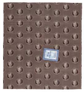 a sample of brown shweshwe fabric featuring Nelson Mandela, with a label reading 'Madiba's Range'