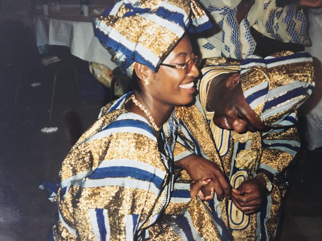 a young Black couple wearing aso-oke dance at their wedding