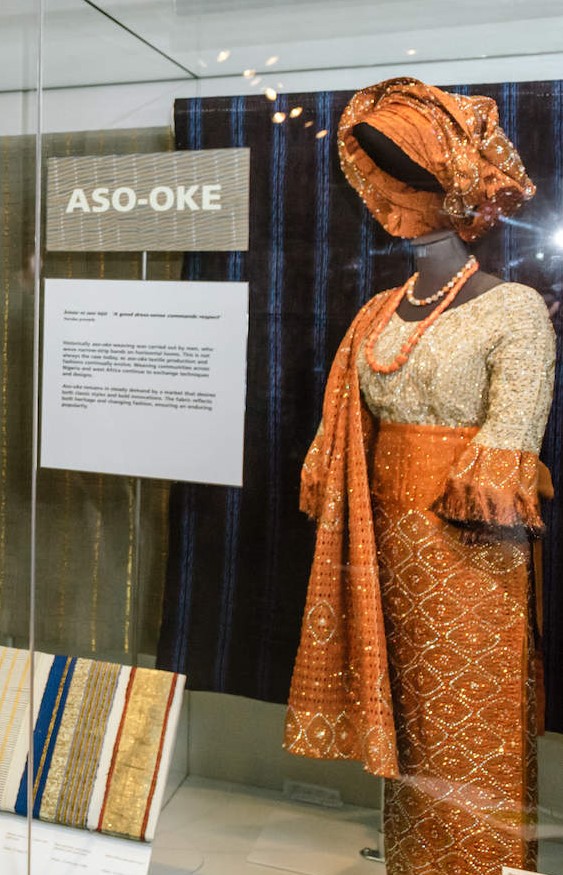 Museum display of orange and gold aso-oke outfit