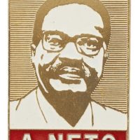 Rectangular shaped metal badge featuring a portrait of Agostinho Neto in white enamel.