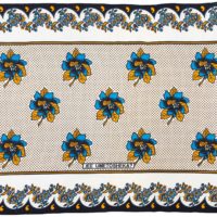 Kanga with a black border, white background, blue and yellow flower designs and yellow spots.
