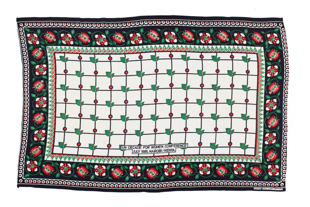 white kanga with black and red floral border, with a central repeat pattern of doves and female symbols