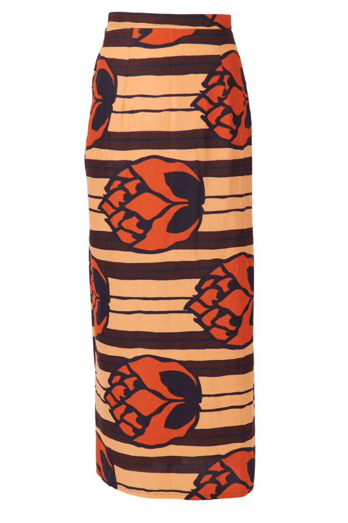 Long wrap skirt, with button fastening and pleats at one side. Orange, peach, brown and black, large floral wax print design.