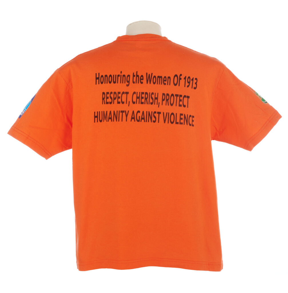 Back view of orange T shirt with the slogan 'Honouring the Women of 1913'
