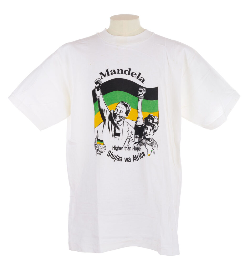 White T shirt with portraits of Nelson and Winnie Mandela, the ANC logo and flag, and text reading 'Mandela, ANC, Higher than Hope, Shuuja wa Africa' in black, green and yellow.