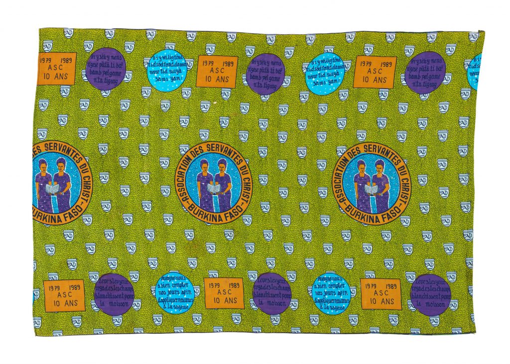 green printed cloth with repeat illustrated pattern of two black women reading from a book