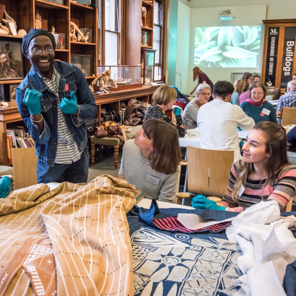 visitors look at textiles laid out on table