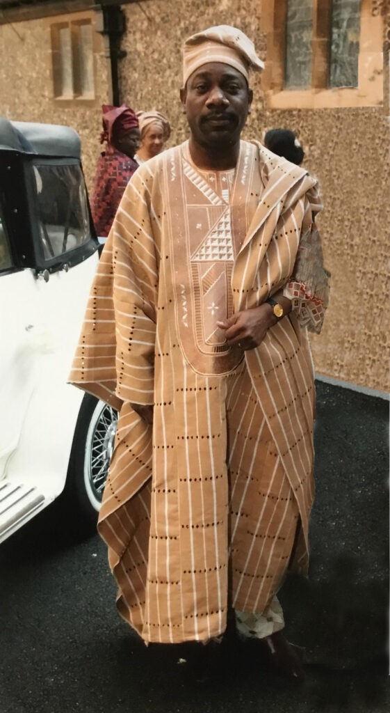 A Nigerian man wearing a beige aso-oke outfit at a wedding