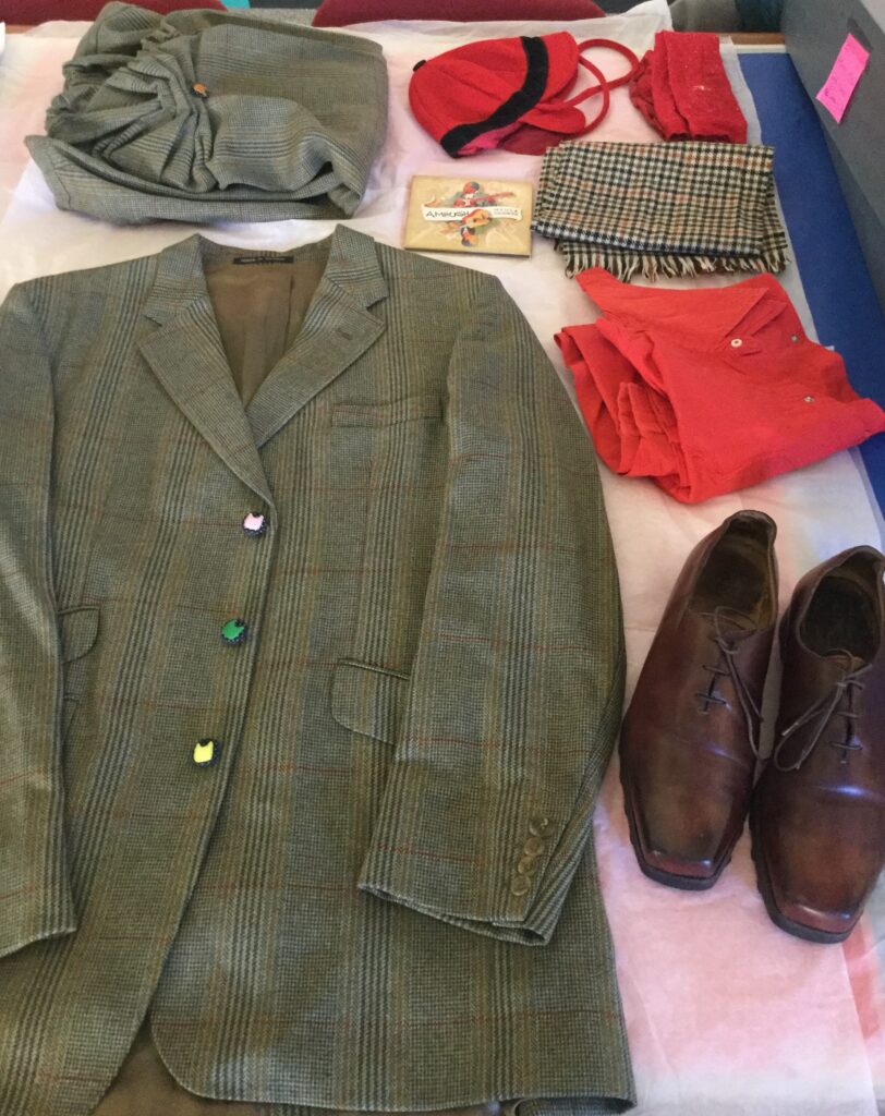 Grey check man's suit and red accessories laid out on table