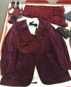 Burgundy velvet jacket and accessories laid out on table