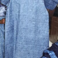 a blue tunic dyed with indigo being held up to the camera