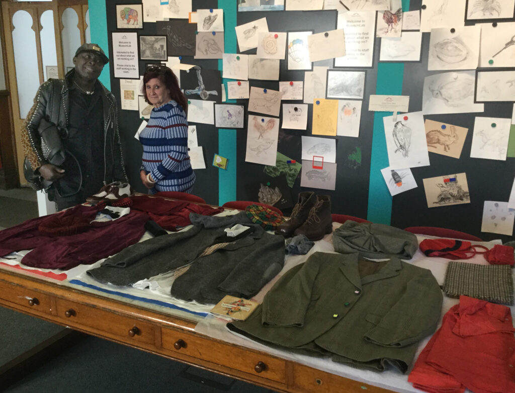 Man and woman standing by a selection of men's clothes laid out on table
